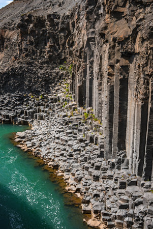 Hexagonal basalt columns meet turquoise water in Iceland gorgeの写真素材