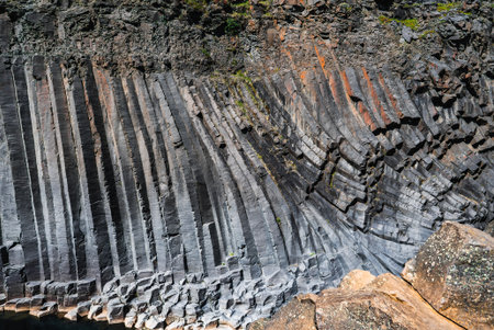 Basalt columns curve along a rocky cliff in Iceland under midday sunの写真素材