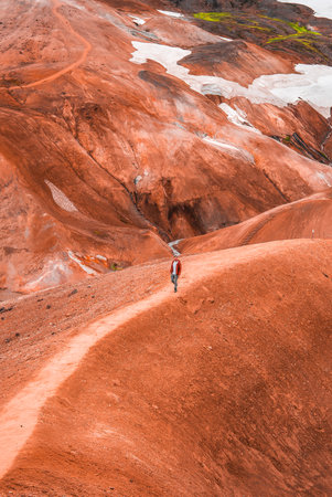 Hiker on rust red rhyolite hills in Landmannalaugar, Icelandの写真素材