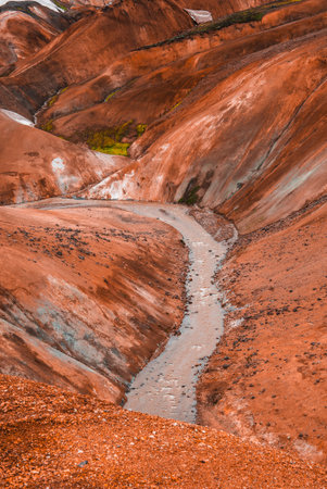 Milky stream through rust red rhyolite hills in Landmannalaugar, Icelandの写真素材