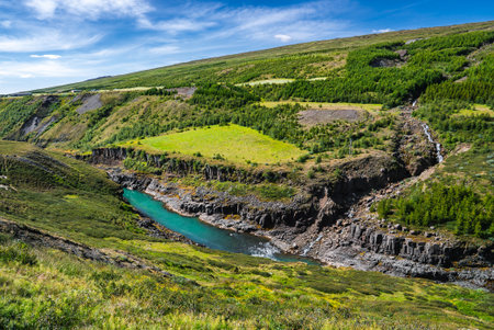 Turquoise river and waterfall in a basalt valley, northern Iceland