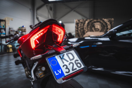 Red Ducati rear with LED taillights and BMW M2 in workshopの写真素材
