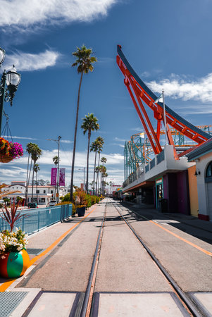 Santa Cruz Beach Boardwalk walkway with roller coaster and palmsの写真素材