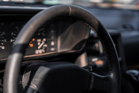 Vintage car interior with worn leather wheel and analog gauges