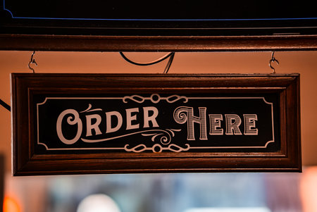 Vintage wood framed Order Here sign hangs by chains indoorsの写真素材