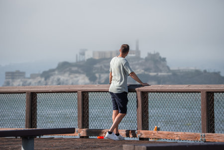 Visitor on pier gazes toward Alcatraz Island in San Franciscoの写真素材