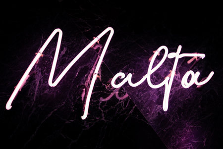 Bright pink neon Malta sign on glossy black wall, diagonal viewの写真素材