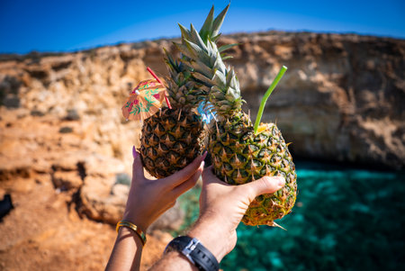 Pineapple drinks toast by limestone cliff at Blue Lagoon, Maltaの写真素材