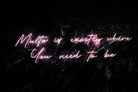 Neon cursive sign glows on black marble wallの写真素材