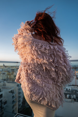 Windblown figure on balcony at sunset facing Gozo channels