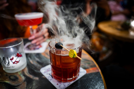 Smoky cocktail with black cherry garnish in a bar at nightの写真素材