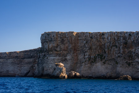 Limestone cliff and boulder by calm waters on Comino Island, Maltaの写真素材