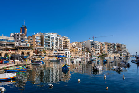Sliema seafront with luzzu boats and high rise by Spinola Bayの写真素材