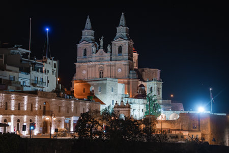 Nighttime view of Baroque church and fortifications in Valletta