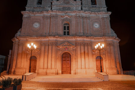 Baroque church facade at night in Mellieha, Malta with warm lightの写真素材