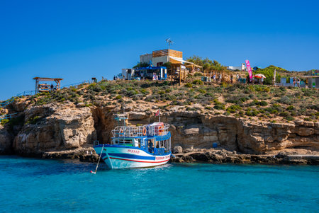 Tour boat below limestone cliffs at Blue Lagoon, Comino, Malta
