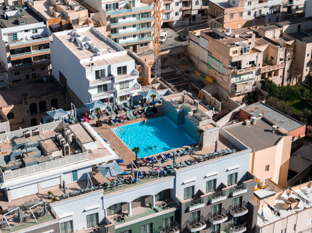 Aerial rooftop pool atop Mellieha hotel amid limestone buildingsの写真素材