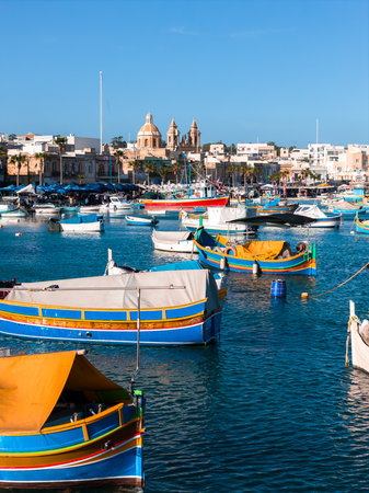 Luzzu boats bob in Marsaxlokk Bay near Parish Church of Our Ladyの写真素材