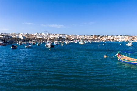 Marsaxlokk harbor with colorful luzzu boats and waterfront promenadeの写真素材