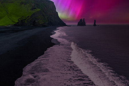 Aurora over Reynisfjara and Reynisdrangar sea stacks near Vik, Iceland