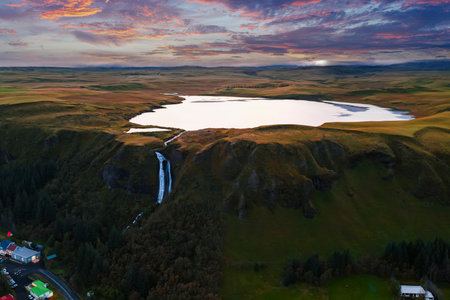 Aerial dusk view of Skogar highland plateau, lake, and waterfallの写真素材