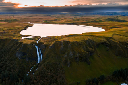 Aerial lake and waterfall on Icelands south coast at sunset lightの写真素材
