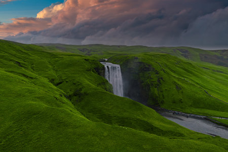 Skogafoss waterfall drops into a winding river in southern Icelandの写真素材