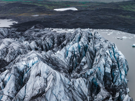 Aerial glacier ridges descend into a milky lagoon in Icelandの写真素材