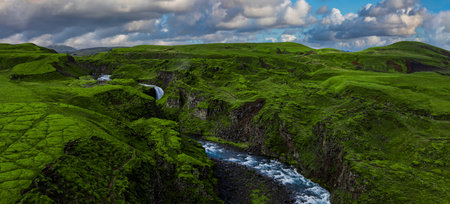 Aerial view of mossy Icelandic canyon with river and waterfallの写真素材