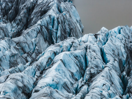 Iceland glacier ridges with ash and lagoon from aerial viewの写真素材