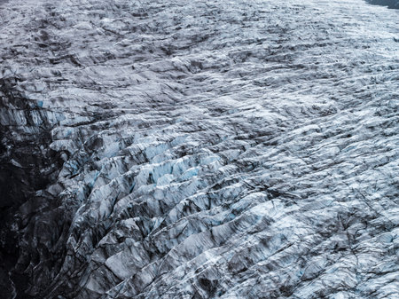 Aerial view of Icelandic glacier crevasses and ash streaked ice ridges