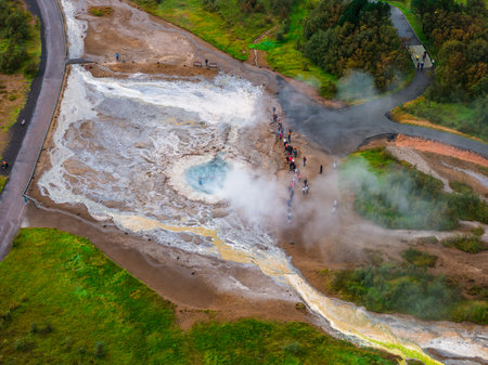 Aerial visitors watch steaming hot spring at Geysir geothermal areaの写真素材