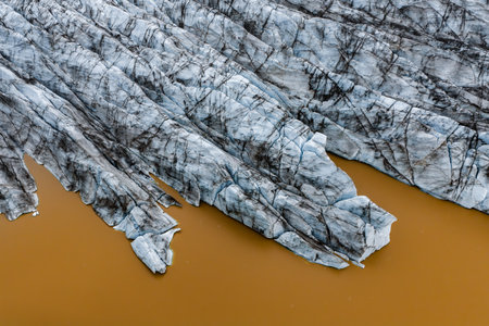 Aerial view of blue gray glacier tongues meeting orange lagoon in Icelandの写真素材