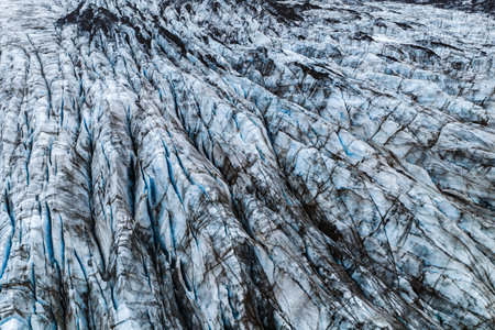 Aerial close view of crevassed Icelandic glacier with ash and blue iceの写真素材