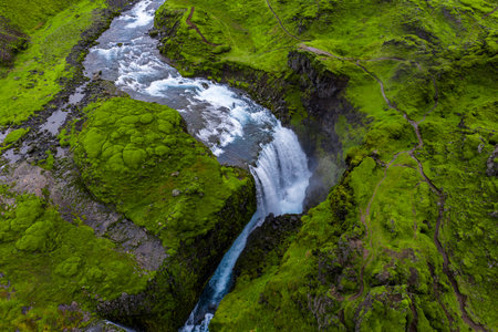 Aerial waterfall plunges through mossy lava gorge near Landmannalaugarの写真素材
