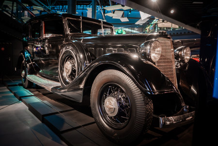 Vintage black luxury sedan displayed under museum gallery lightingの写真素材