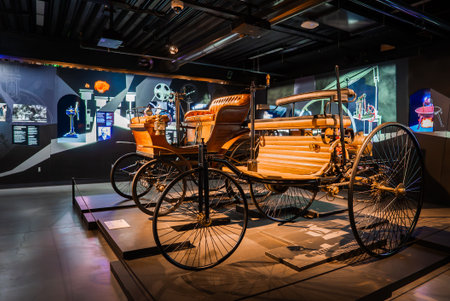 Warmly lit auto museum gallery with ornate early motorcars on displayの写真素材