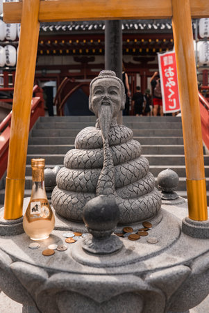 Serpent sage statue and offerings at Tokyo temple entrance stepsの写真素材
