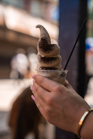 Hand holding soft serve with cocoa near deerの写真素材