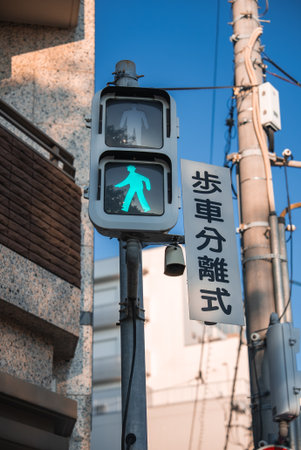 Japanese pedestrian signal glows green beside kanji signの写真素材