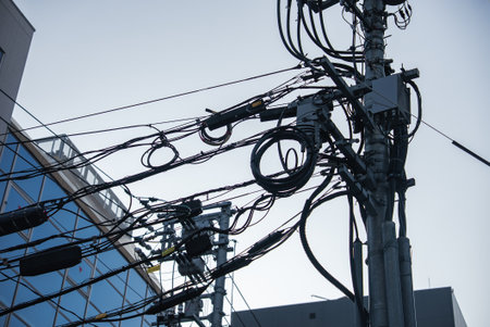 Urban power pole wrapped in cables near glass building in Hiroshima