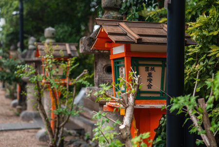 Stone lanterns and orange wooden lamps along a Kyoto shrine pathの写真素材