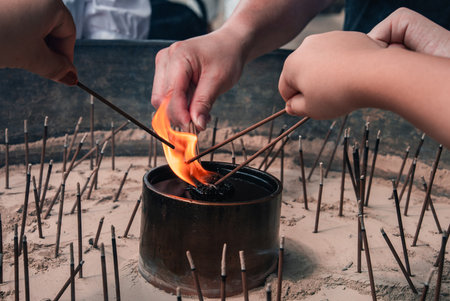 Hands light incense at a metal brazier in a sand filled burner, Naraの写真素材