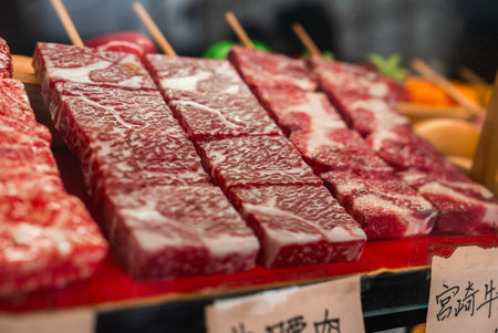 Wagyu beef skewers on red tray at Kyoto Nishiki Market stallの写真素材