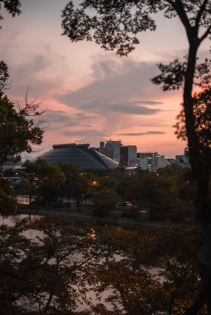 Osaka jo Hall at dusk across water with treetops and city lightsの写真素材