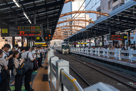JR train approaches Osaka platform with rush hour queues and signsの写真素材