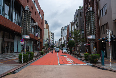 Tokyo side street with red bus lane and cylindrical lamp towersの写真素材