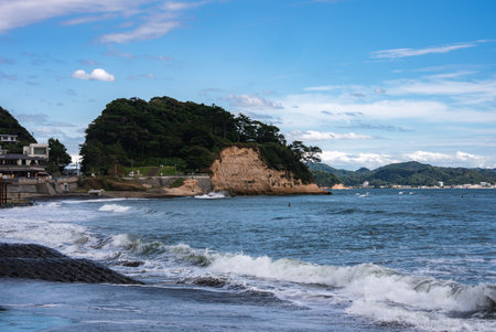 Rugged Kamakura coastline with headland, waves, and seaside housesの写真素材