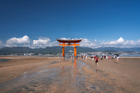 Visitors walk to Itsukushima Shrine torii gate on Miyajima at low tideの写真素材