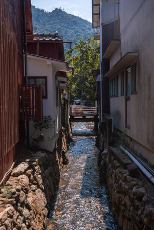 Narrow stream between wooden buildings on Miyajima near Hiroshimaの写真素材